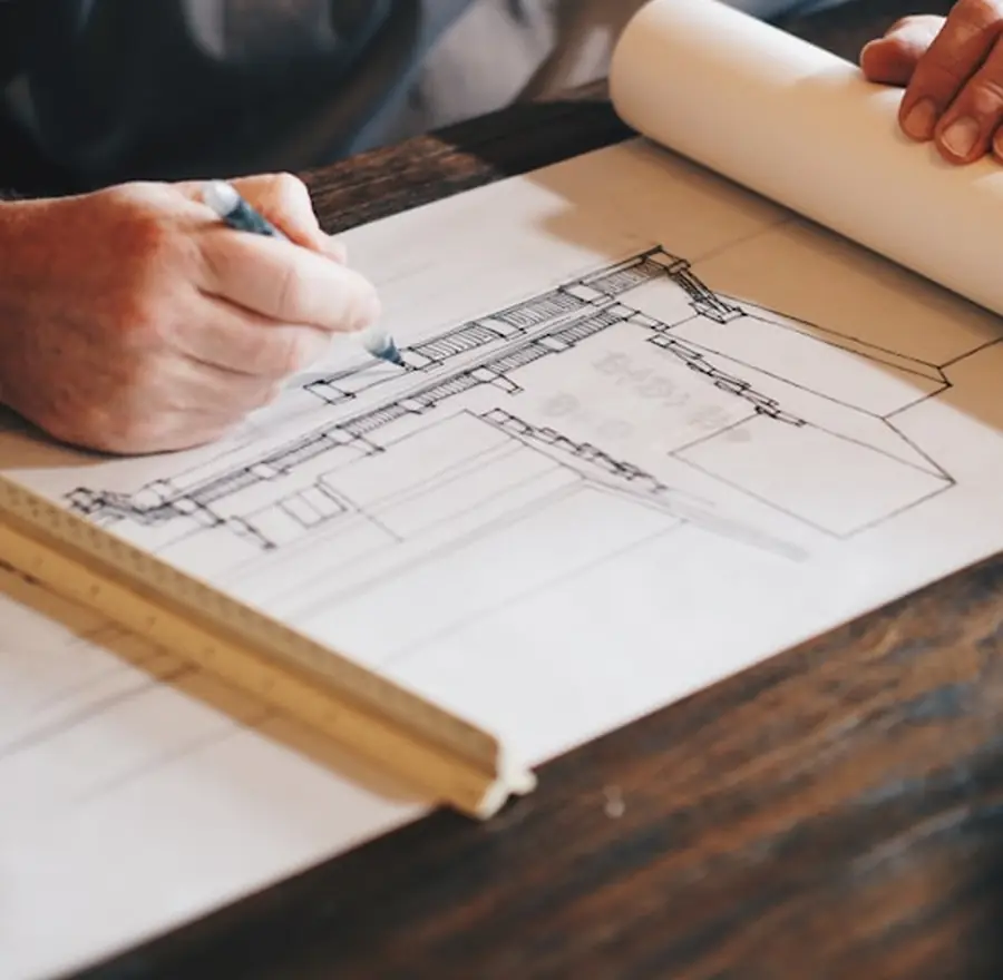 Mãos analisando uma planta técnica sobre a mesa
